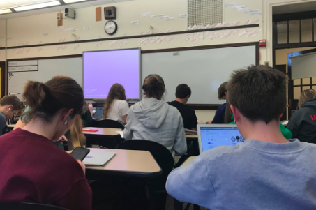 Scrolling by: Right before the bell, students Quinn Brigner (10) and Patrick Sullivan (10) spend time on their devices, rather than conversing with one another.